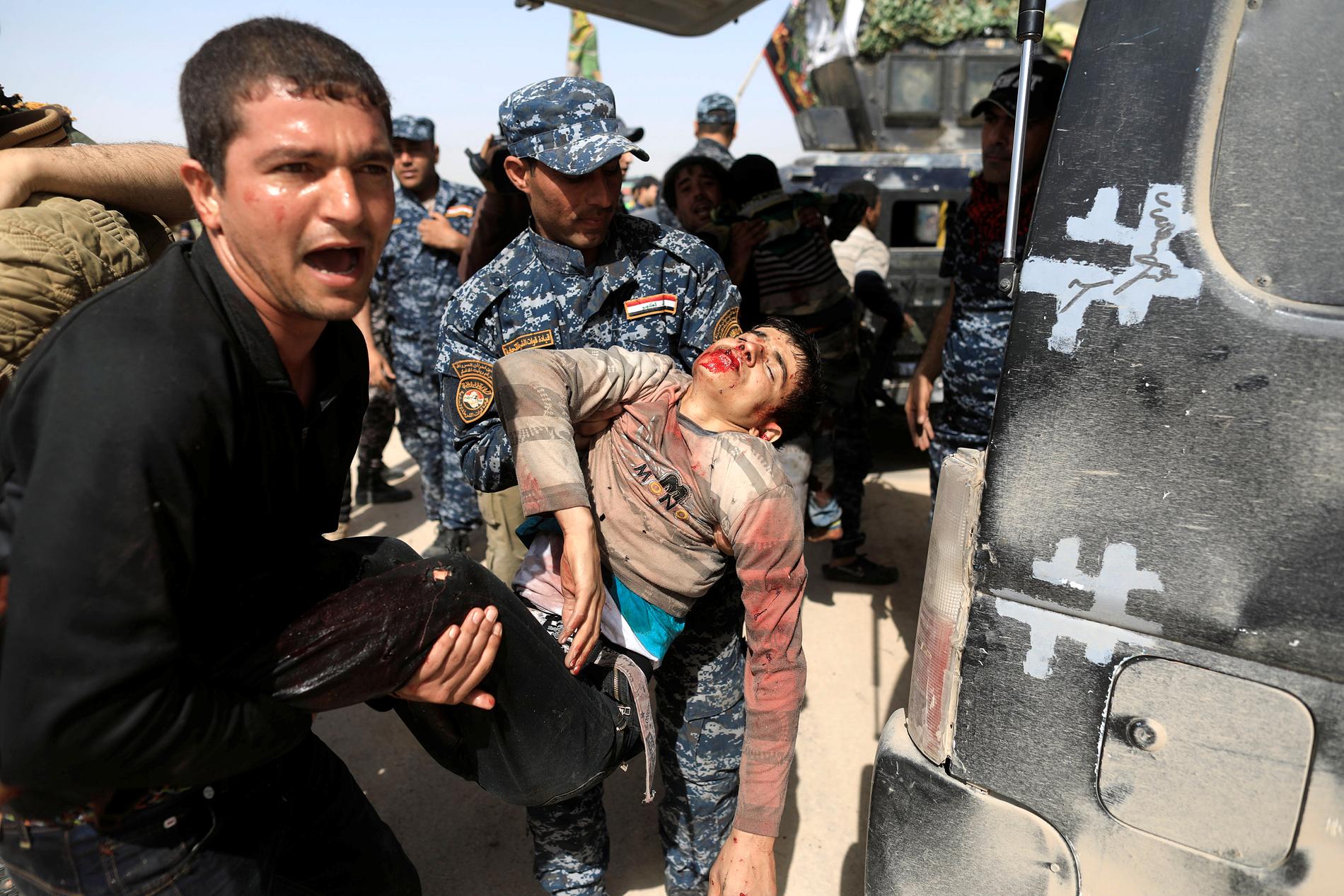Irakisk federal polis tar hand om skadade civila i västra Mosul.