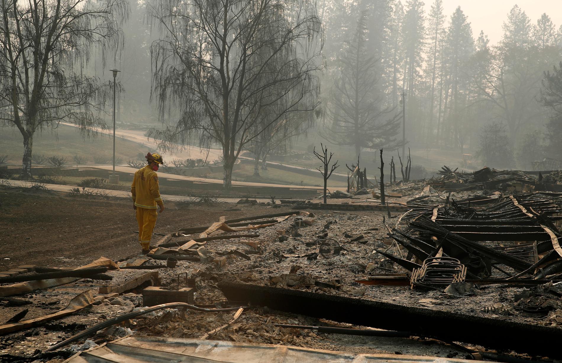 En brandman söker igenom ett område efter den så kallade Camp Fire-branden.