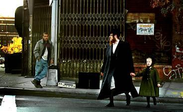 En ortodox jude och en flicka korsar en gata i Williamsburg, New York. I bakgrunden står en man och försöker sälja en stereo.