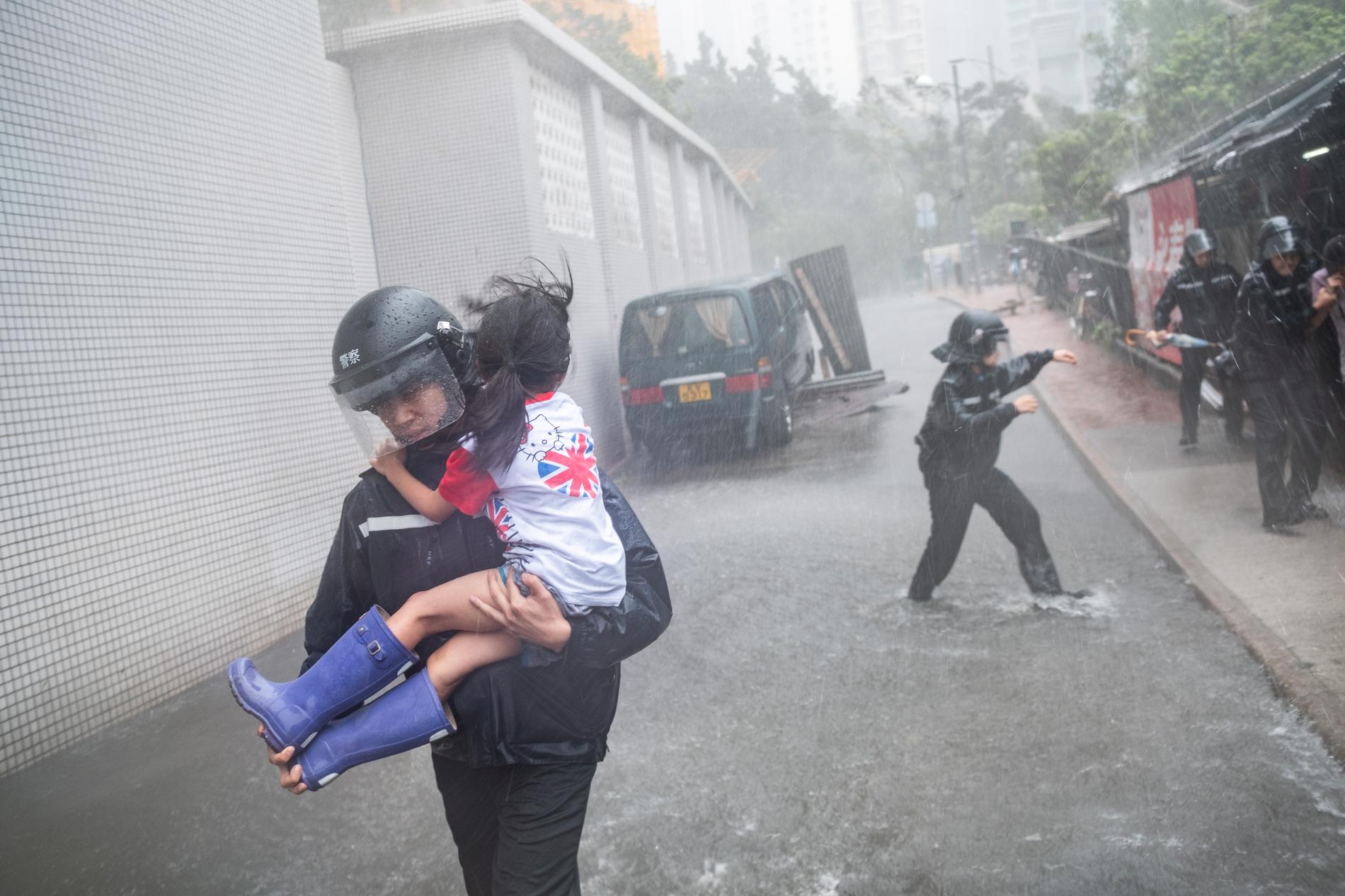 En polisman bär ut en flicka från en kollapsad skolbyggnad i Hongkong. 