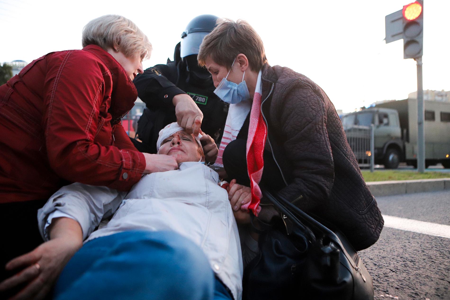 En kvinna som skadades vid demonstrationer i Minsk på onsdagen tas om hand av andra demonstranter.