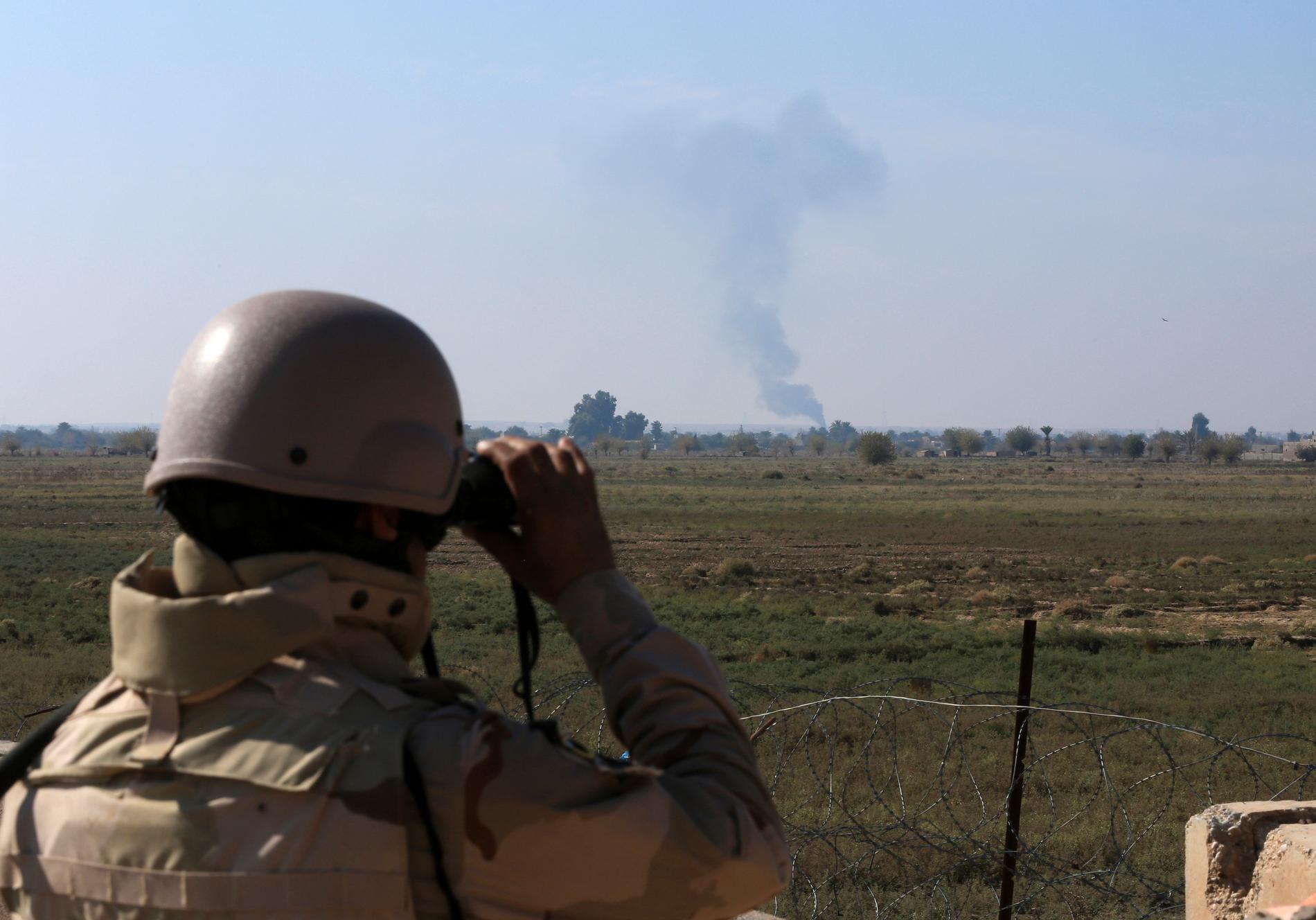 En irakisk soldat riktar kikaren mot en rökpelare efter ett flyganfall mot Islamiska staten (IS), vid gränsen mot Syrien. Arkivbild.