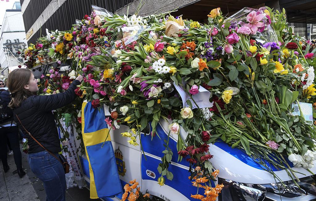 Blommor placeras på en polisbil utanför Åhlens (där lastbilen körde in i varuhuset) i samband med manifestationen för kärlek och omtanke på Sergels torg i Stockholm på söndagen efter terrorattacken på Drottninggatan. 4 personer omkom vid fredagens terrorattack.