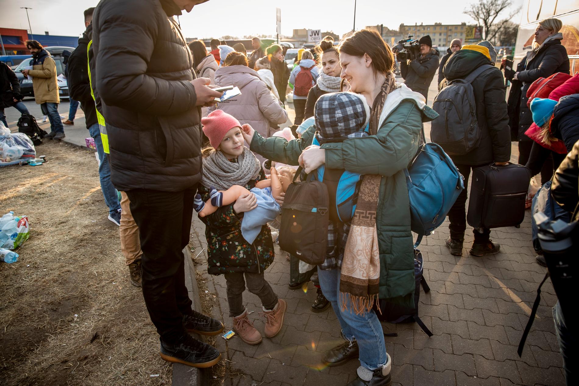 En ukrainsk familj som just kommit av en buss som tagit dem från gränsen. Nu väntar de på att få komma vidare, få mat och husrum. 