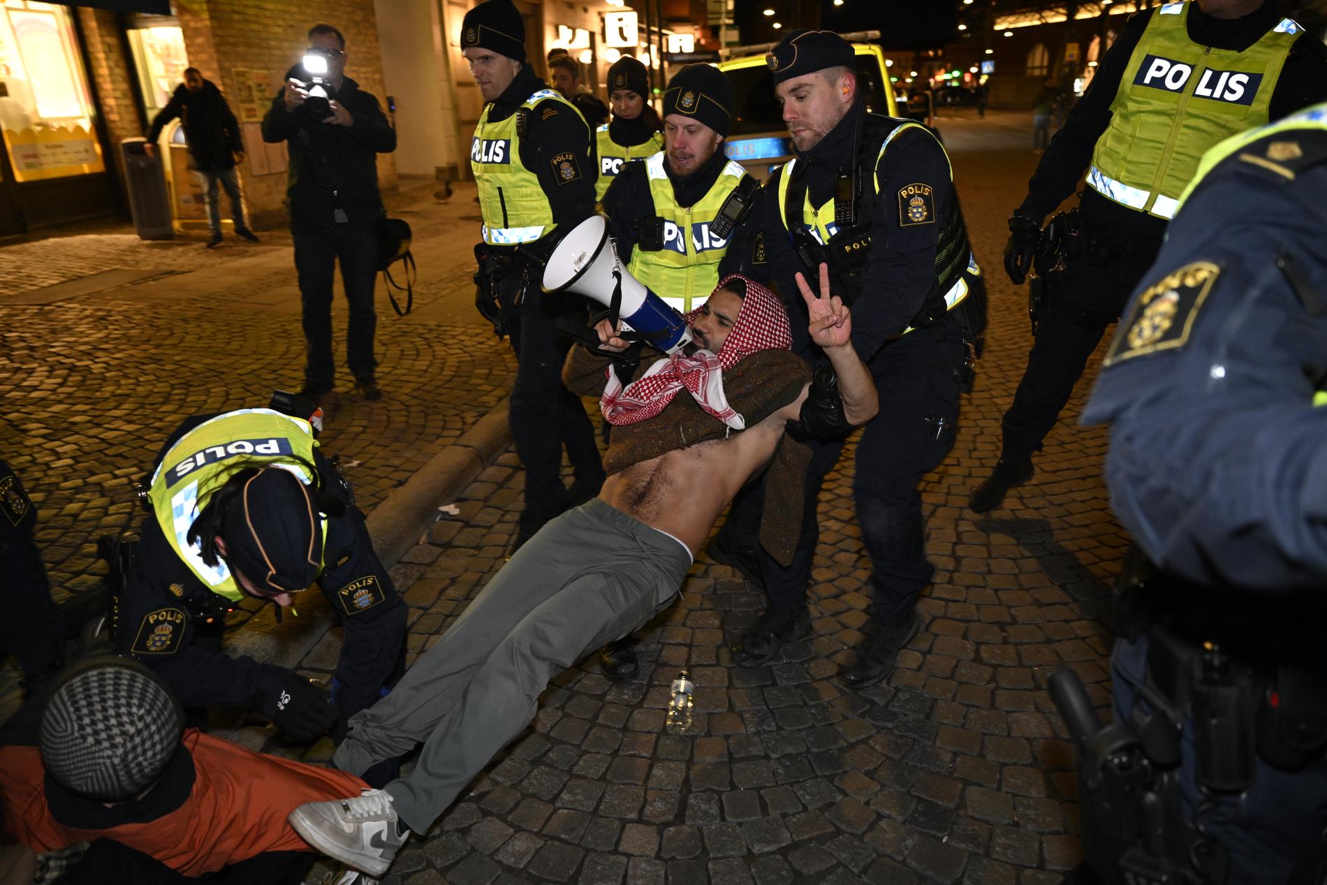 En person som protesterar på Stortorget tas om hand av polisen i samband med att statsminister Ulf Kristersson besöker Studentafton i Stadshallen i Lund.