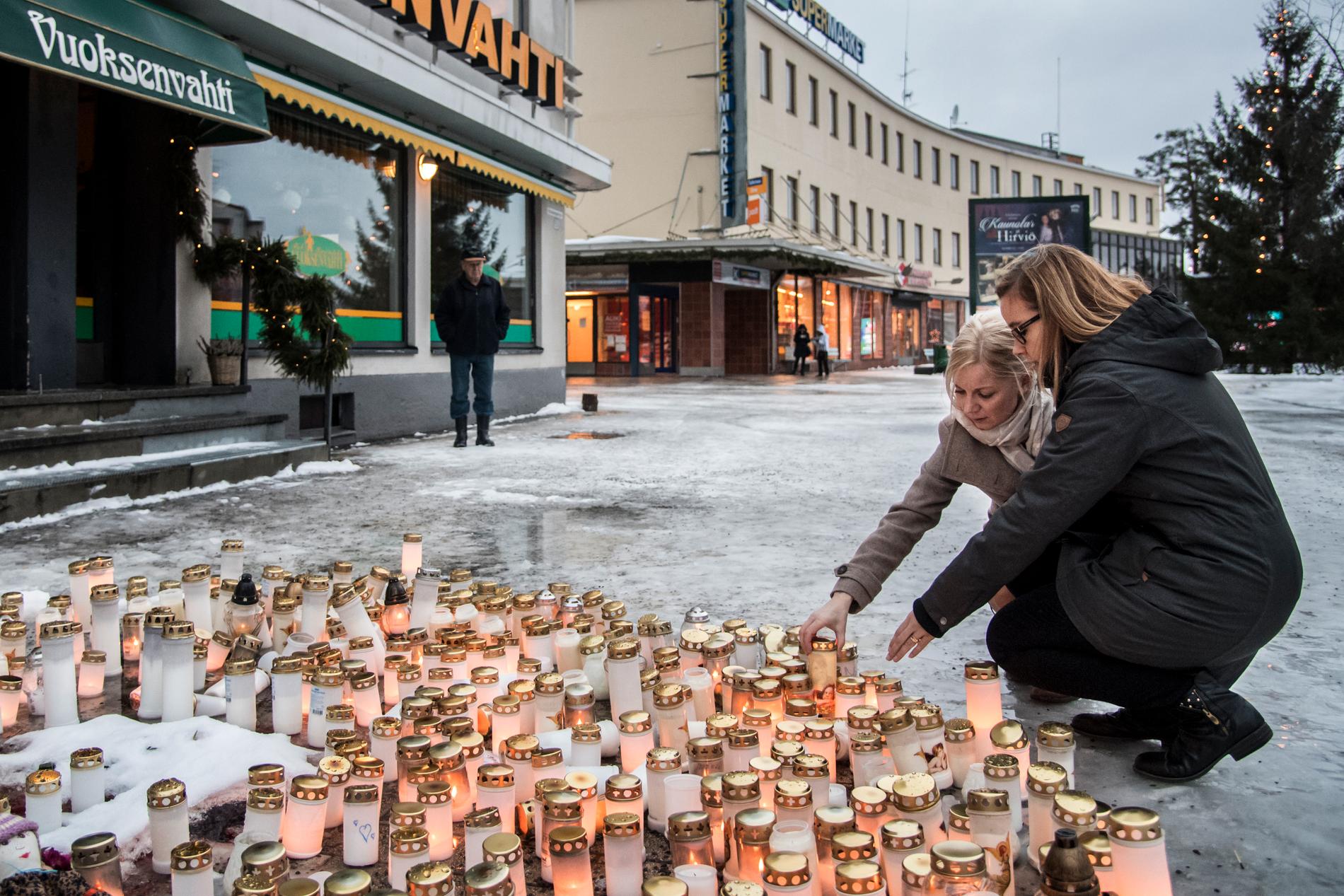 Niina Viljakainen, 40, och Sari Suhonen, 33, sätter ned ljus vid platsen där tre personer sköts till döds natten till söndagen.