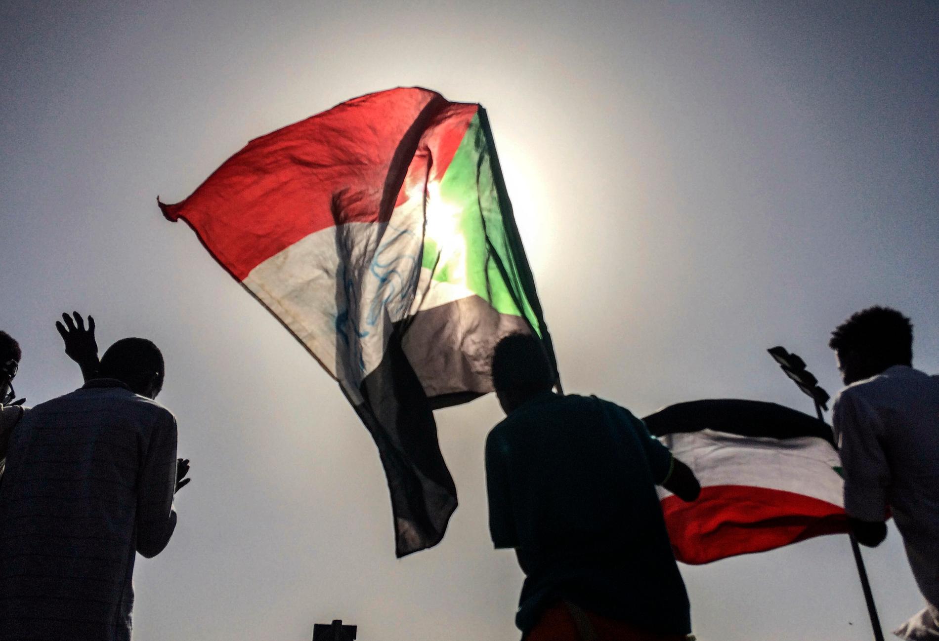 Sudanesiska demonstranter med landets flagga utanför militärens huvudkvarter i Khartum.