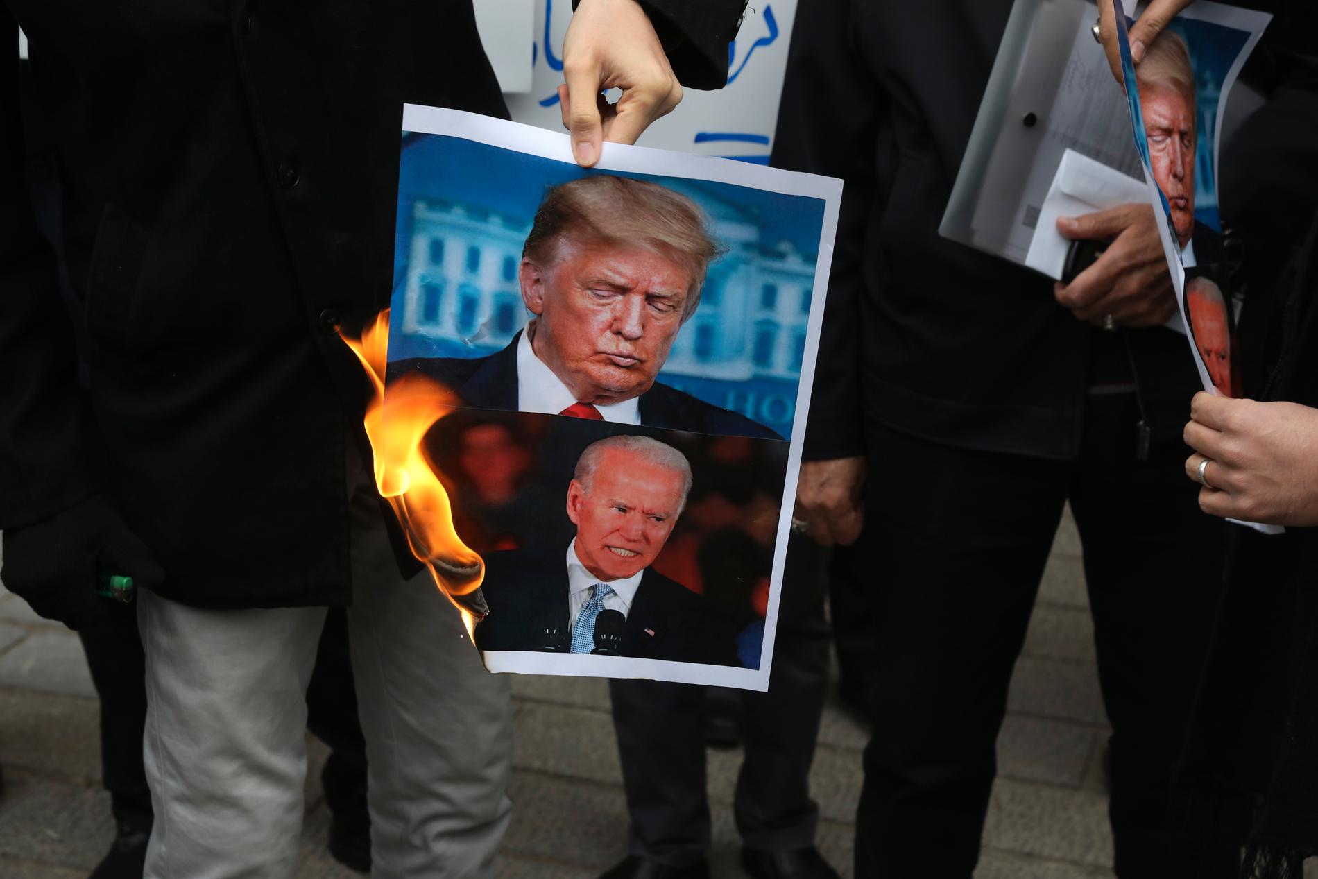 Demonstranter bränner en bild på USA:s president Donald Trump och tillträdande president Joe Biden under en protest framför det iranska utrikesdepartementet i lördags – dagen efter mordet på Mohsen Fakhrizadeh.