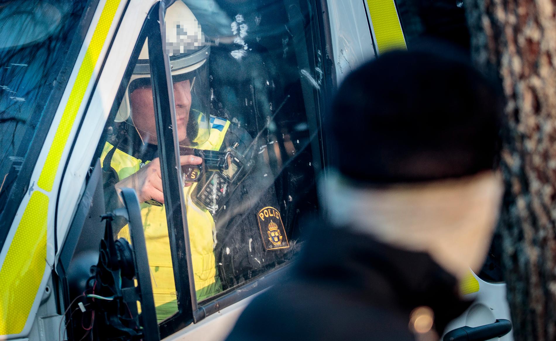 En polis som blivit ensam kvar i en av polisbussarna riktar sitt vapen ut genom vindrutan vid fredagens upplopp i Örebro.