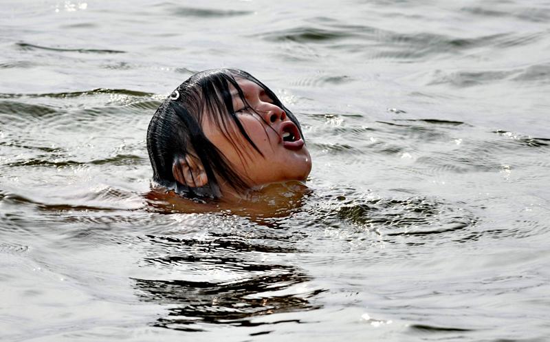Kämpar Huang Li tar ett djupt andetag och håller huvudet ovanför vattenytan medan hon i tre timmar simmar med händer och fötter bundna.