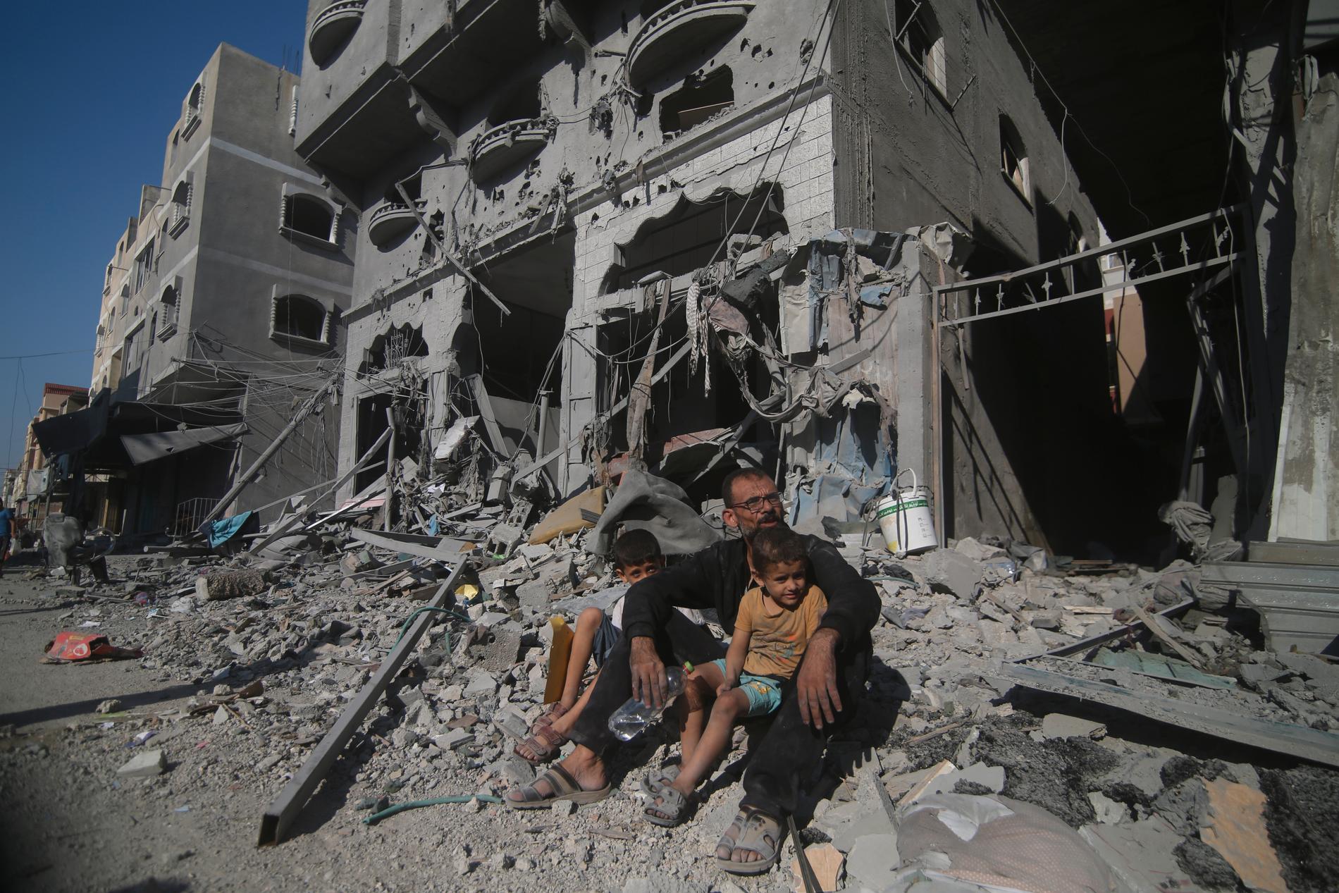 En palestinsk familj sitter utanför sitt före detta hem efter israeliska flygangrepp i Rafah.