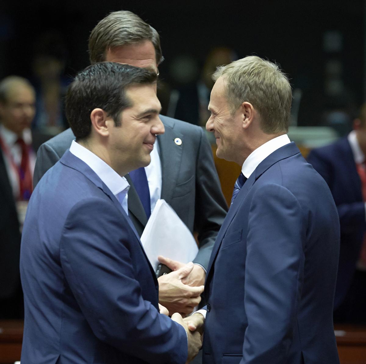 Tsipras och Tusk skakar hand under EU-toppmötet i Bryssel.