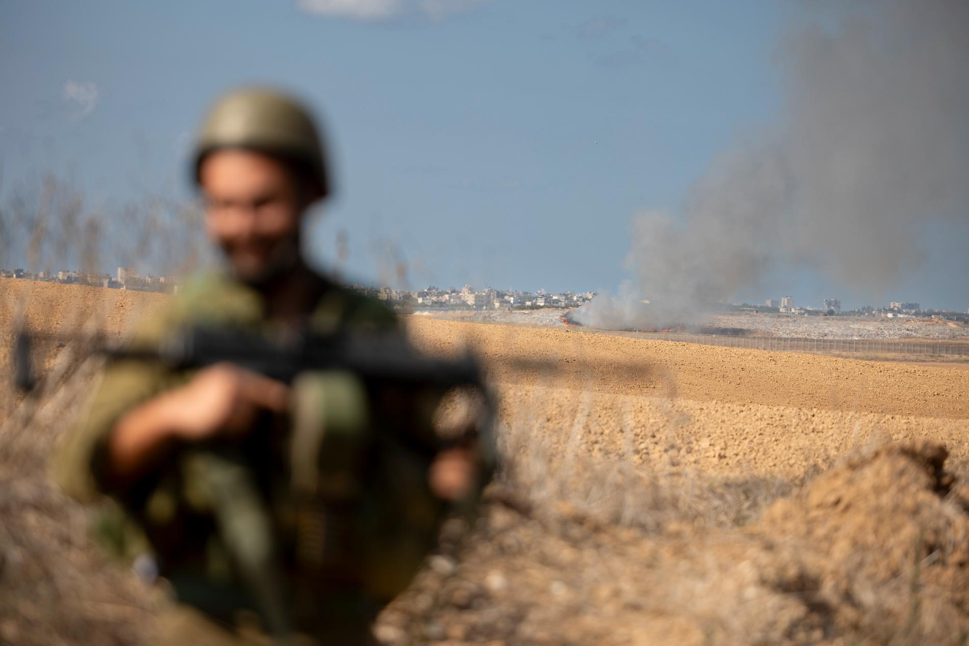 Be’eri, Israel. En soldat med frontlinjen och Gaza i bakgrunden under israelisk bombning. 