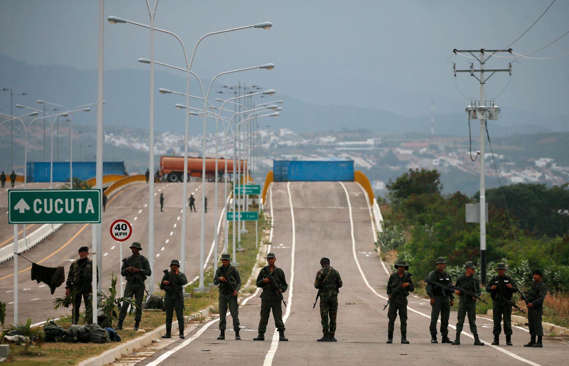 Venezuelanska soldater framför ett tankbilssläp och två stora containrar som spärrar av gränsbron över floden Táchira mellan Venezuela och Colombia.