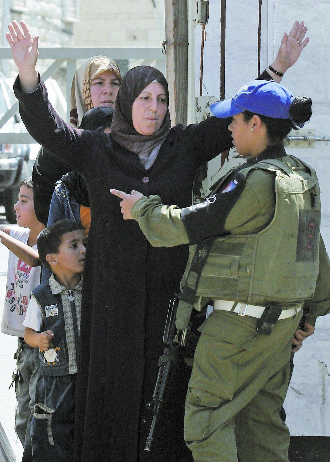 En palestinsk kvinna visiteras av en israelisk soldat i Hebron på Västbanken.