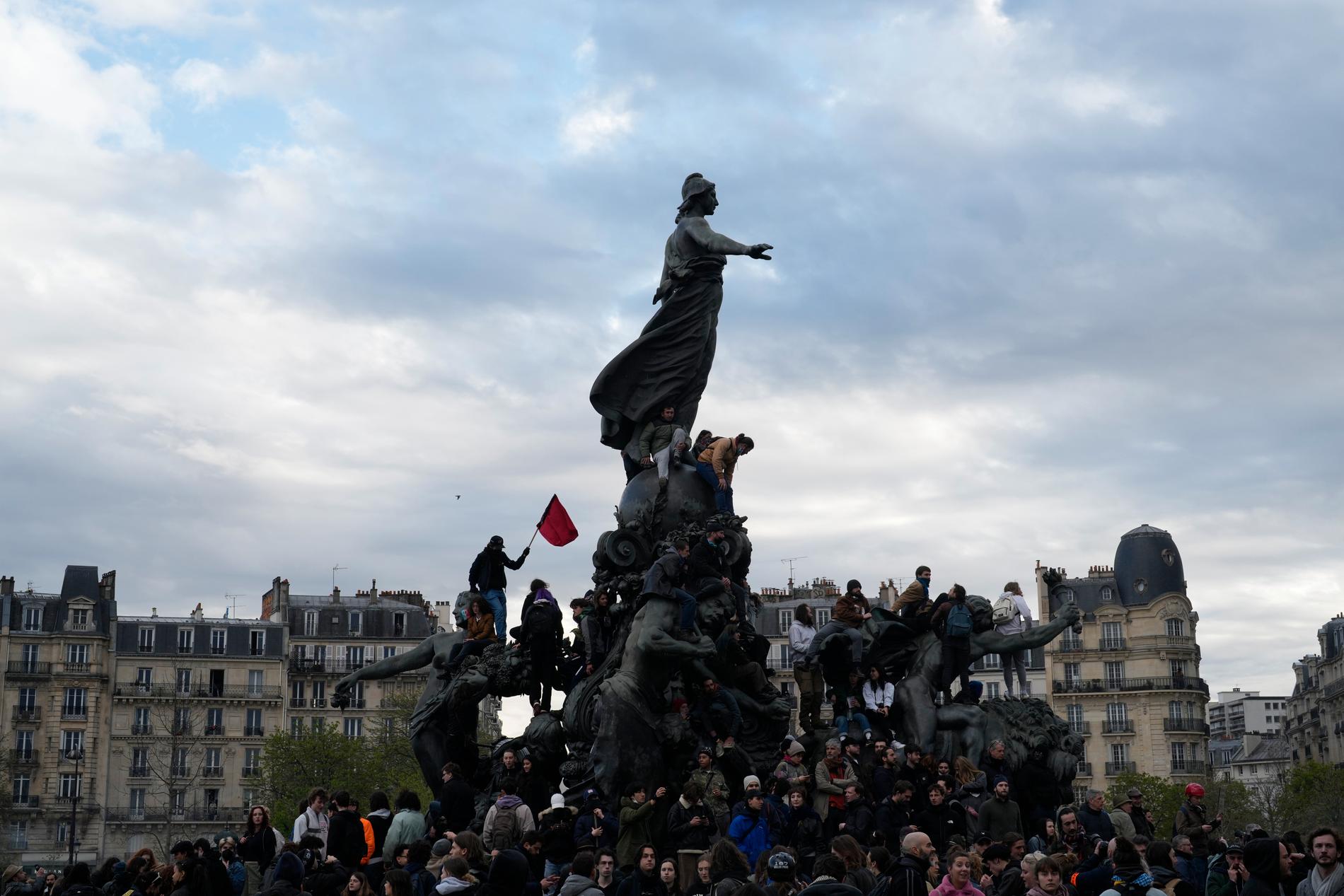 Demonstranter klättrar upp på Place de la Nation i Paris, under protesterna mot president Emanuel Macrons höjning av pensionsåldern.