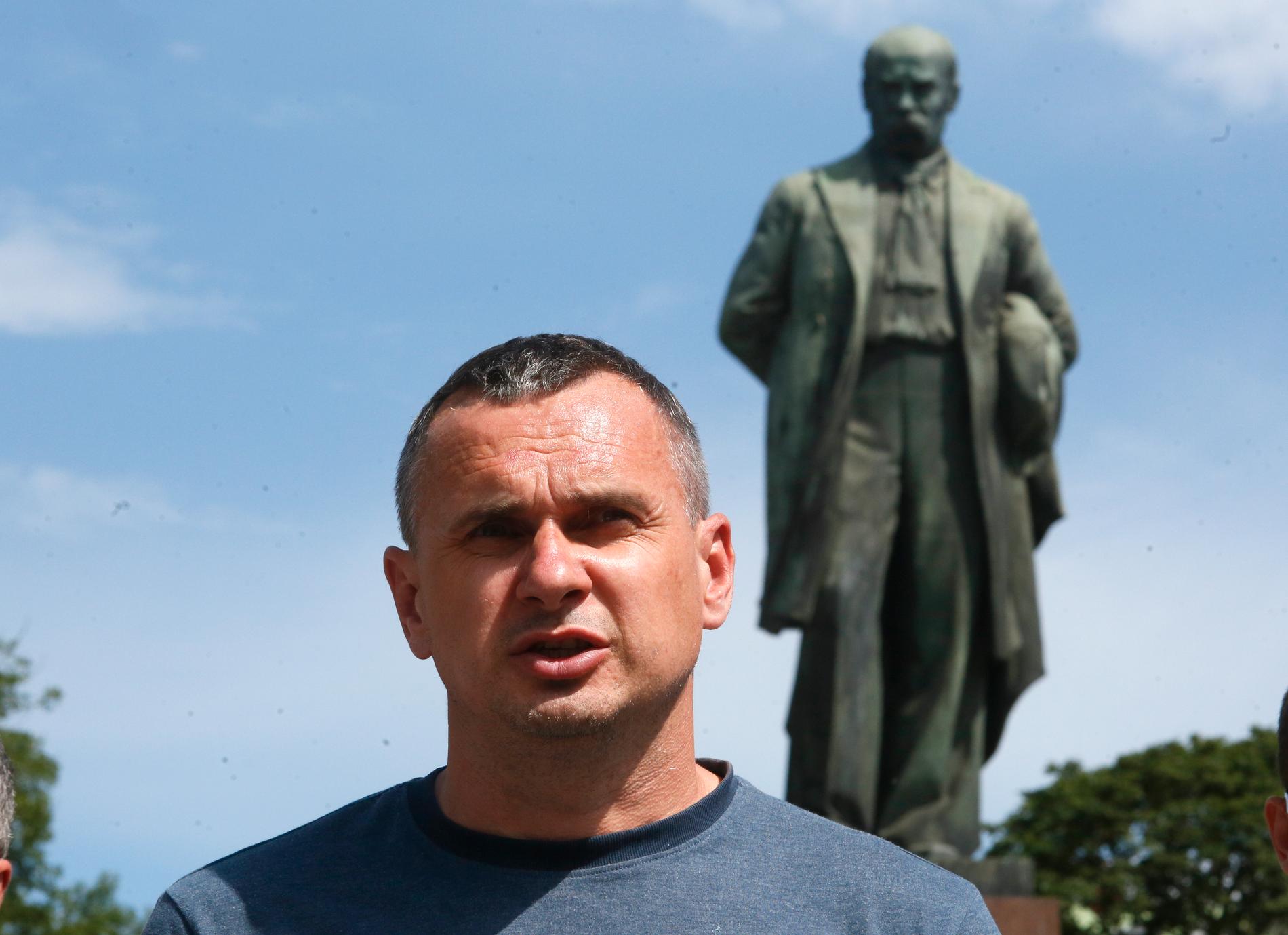 Den ukrainske regissören Oleg Sentsov framför en staty av nationalpoeten Taras Sjevtjenko 2020. Nu har filmmakaren skadats vid fronten i kriget. Arkivbild.