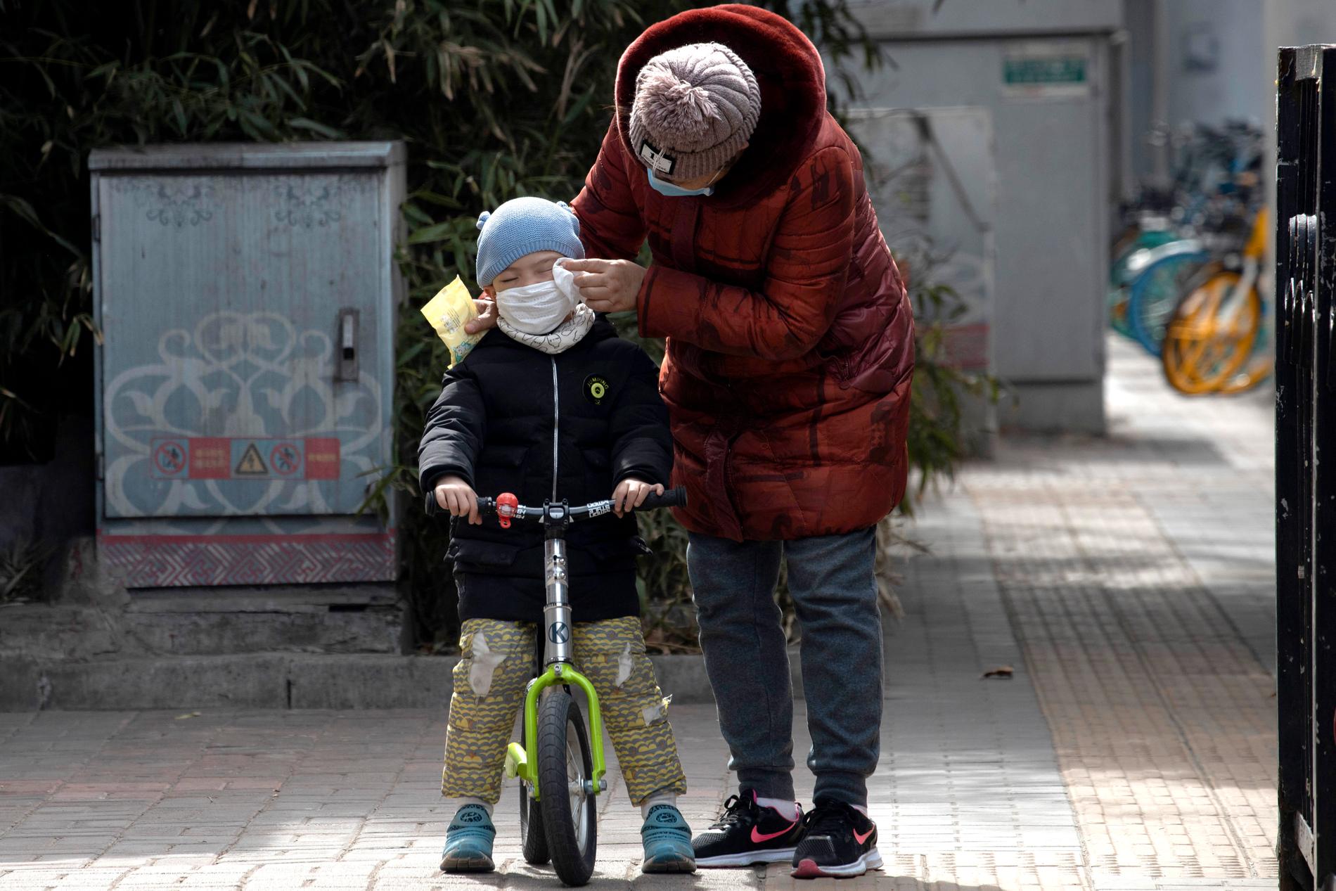En kvinna hjälper ett barn på en gata i Peking.