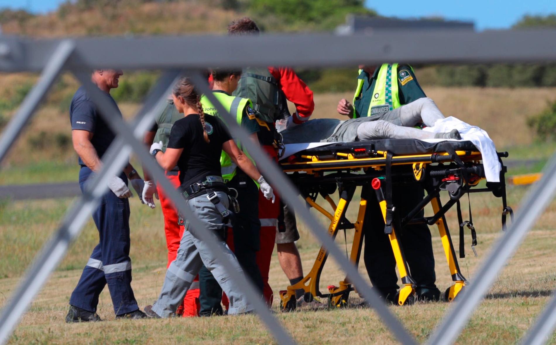 Räddningspersonal tar hand om en skadad person som anlänt till Whakatane flygfält efter vulkanutbrottet på White Island, Nya Zeeland.