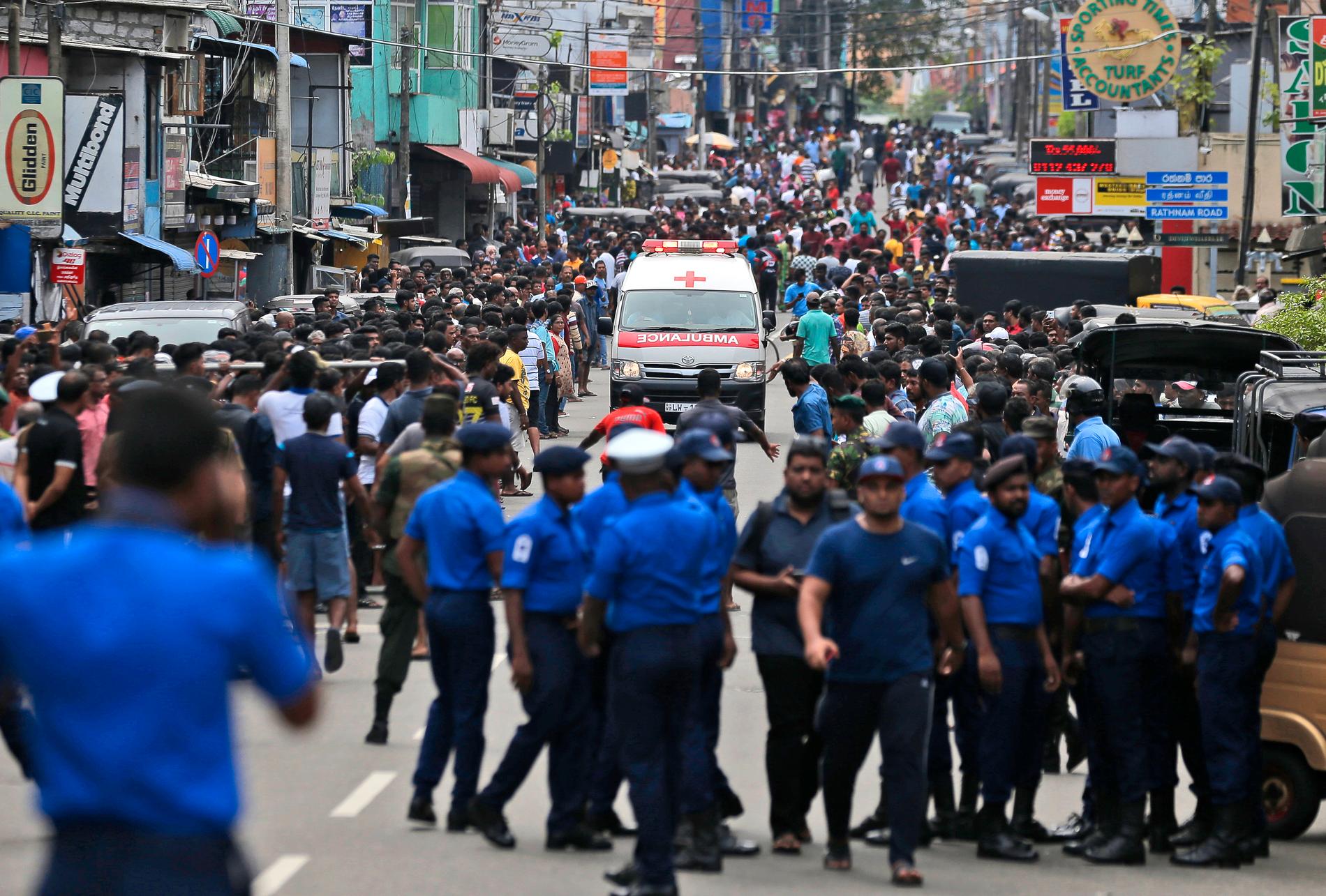 Ambulans åker genom folkhav i Colombo.