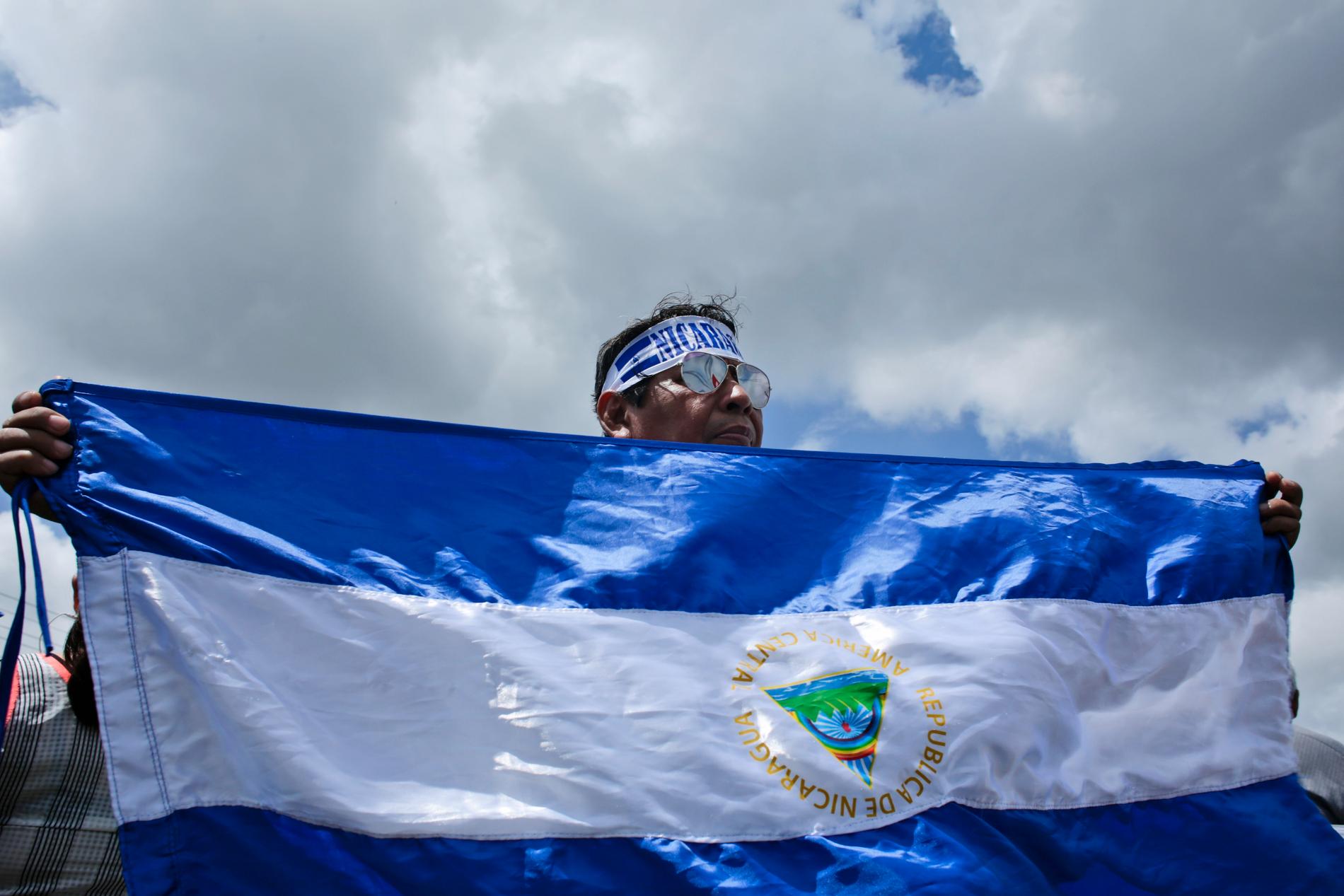 En demonstrant håller upp i flagga under en demonstration för stöd för journalister i Nicaragua 2018.