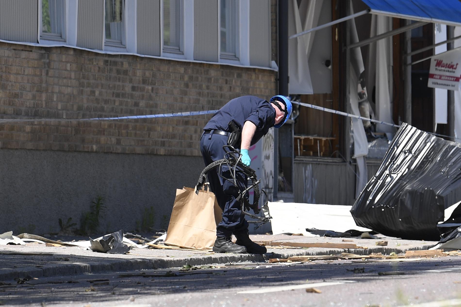 En av polisens tekniker ses bärandes på vad som ser ut som cykeldelar efter explosionen i Linköping.