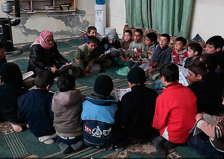En IS-predikant lär syrianska pojkar i Tel Abyad att recitera koranen. Foto: AP
