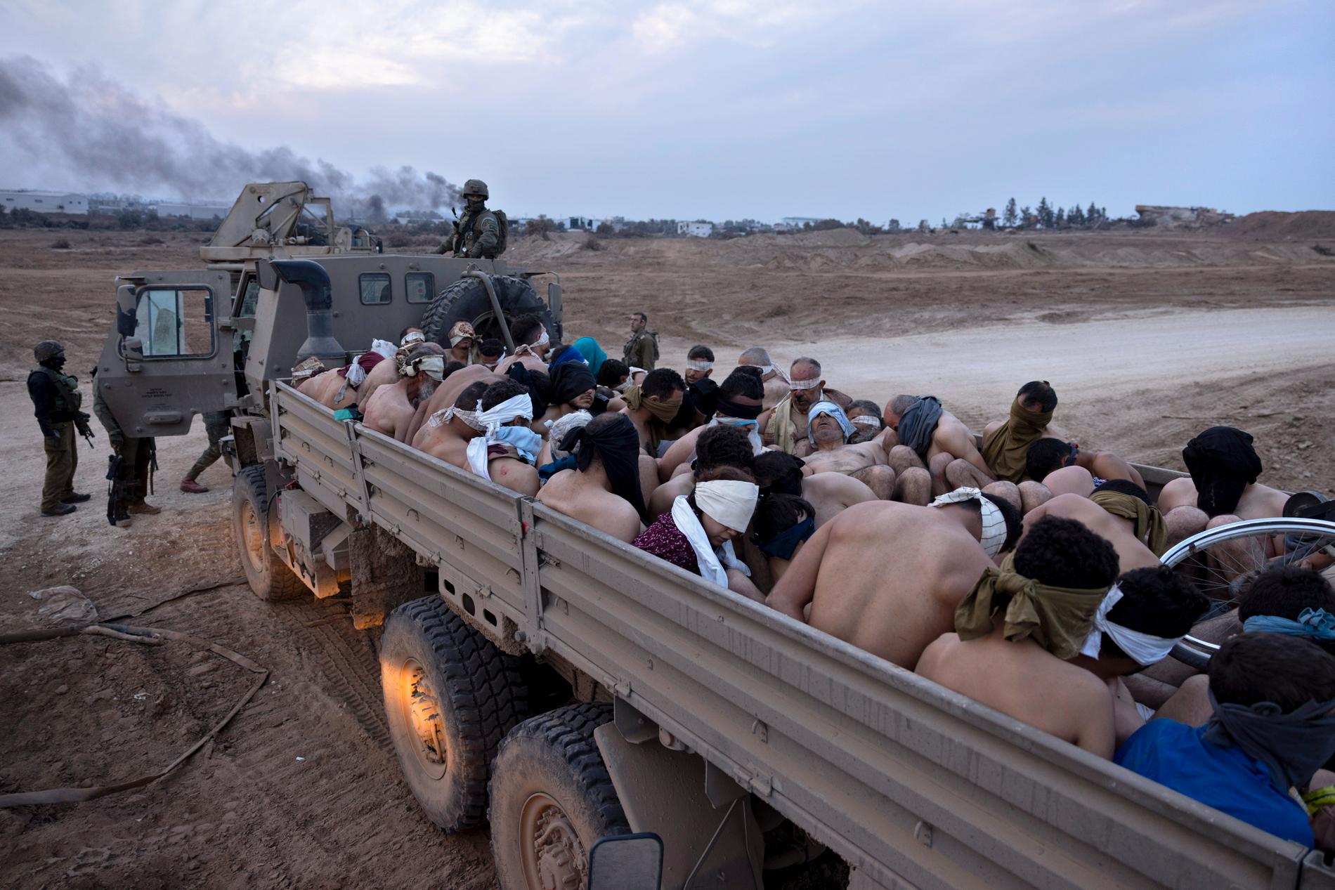 Israeliska soldater står vid en lastbil med palestinska fångar. 