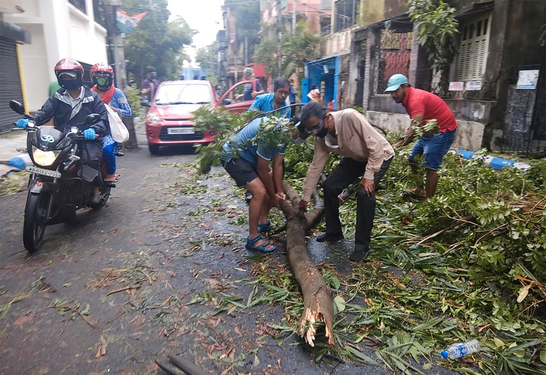 Invånare i Kolkata röjer gatorna från nedfallna träd.