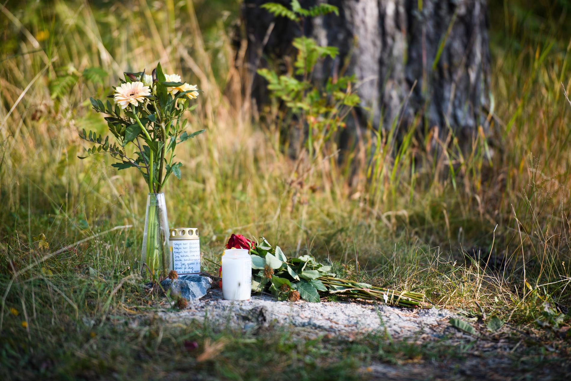Blommor och ljus vid minnesplatsen för den mördade kvinnan.