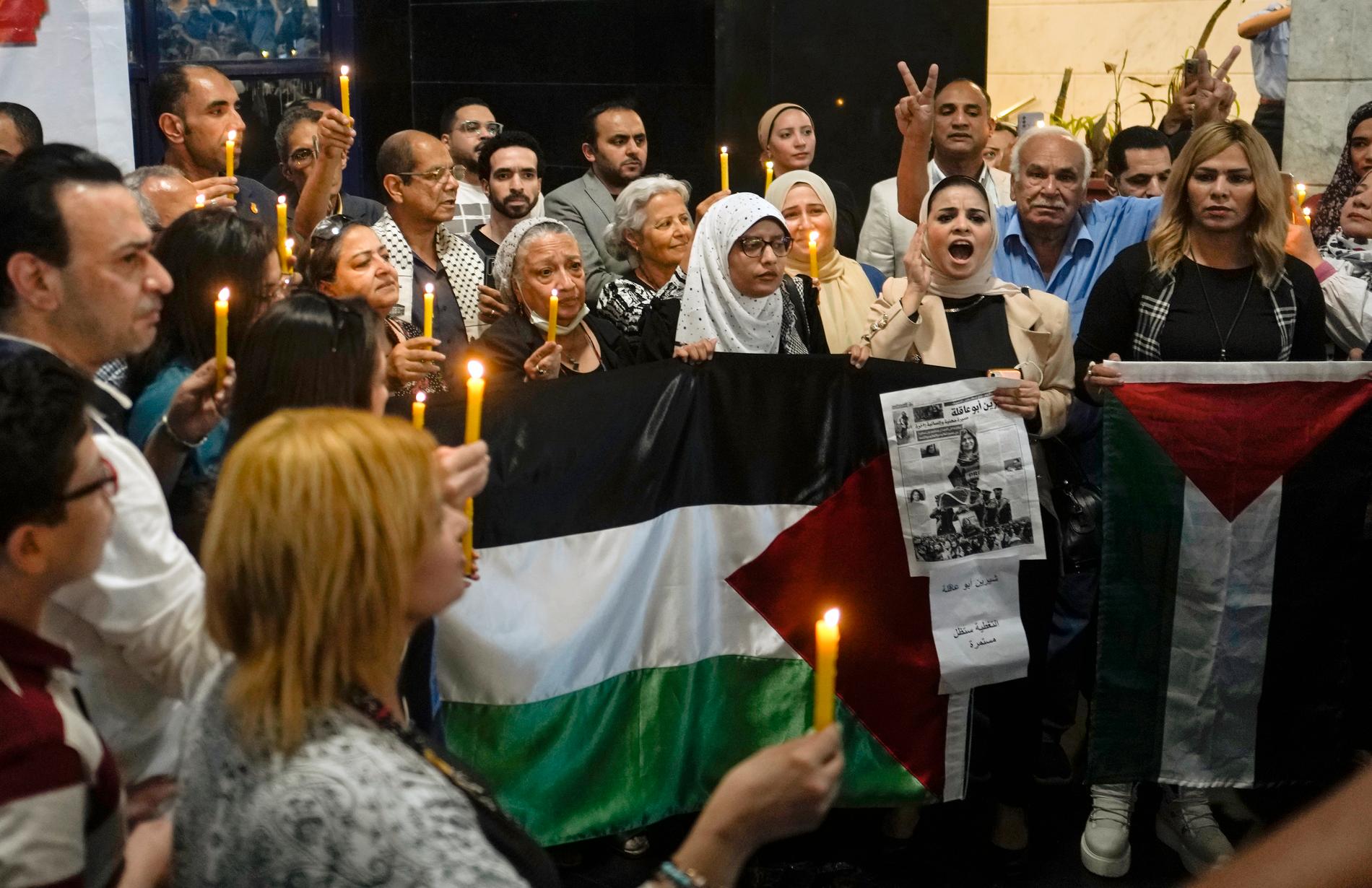 Människor håller tända ljus och palestinska flaggor vid en minnesstund för den dödade journalisten Shireen Abu Akleh. Bilden togs den 17 maj, en knapp vecka efter det att hon skjutits ihjäl i samband med en israelisk räd i Jenin.