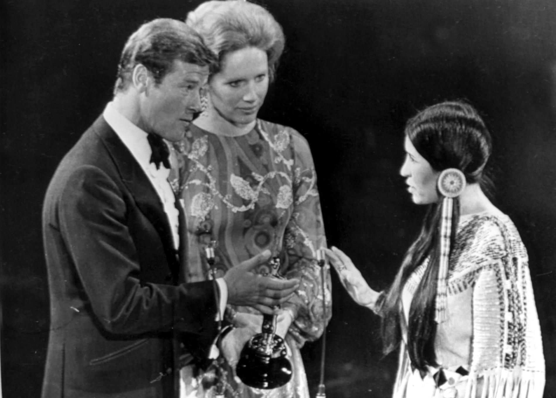 Prisutdelarna Roger Moore och Liv Ullman med Sacheen Littlefeather på Oscarsgalan 1973.