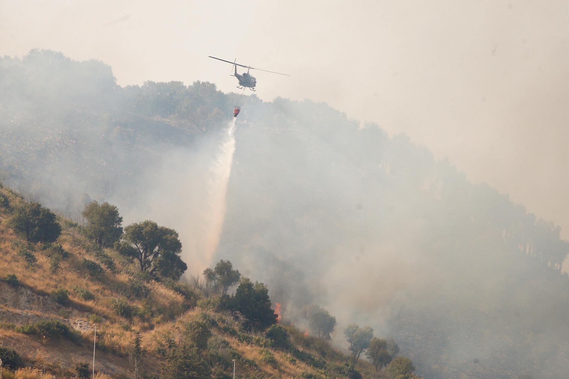 En helikopter deltar i släckningsarbetet av en markbrand några mil från Italiens huvudstad Rom i augusti förra året.