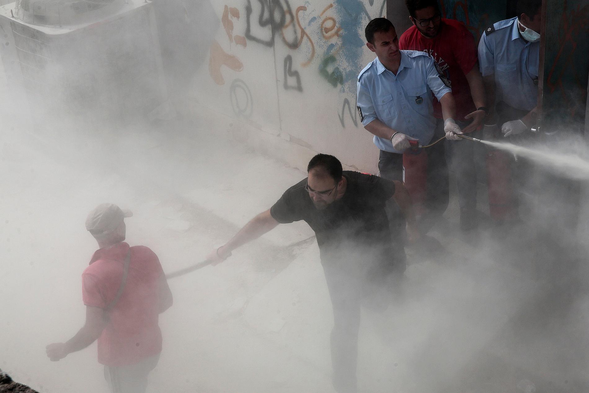 Polisen sprutar med  brandsläckare och använder batong mot flyktingar på fotbollsstadium på kos, Grekland.