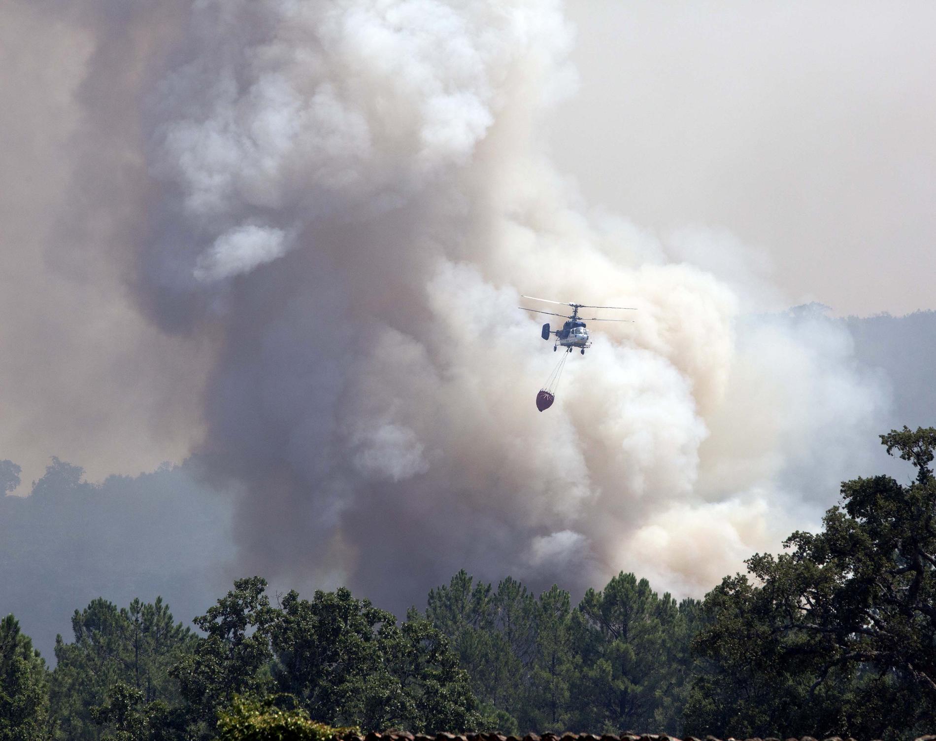 En helikopter transporterar vatten i närheten av staden Hoyos där branden härjar.