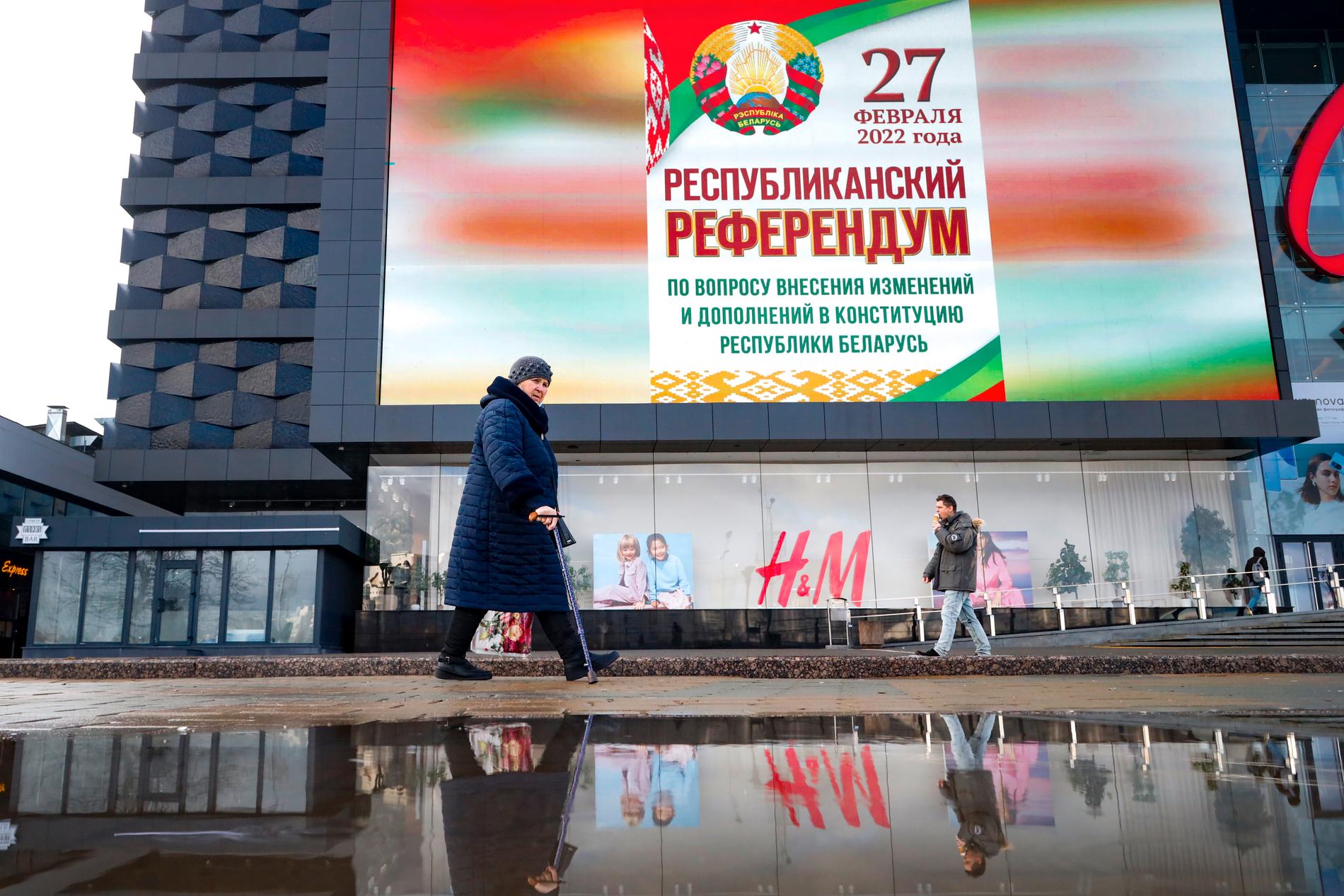 Vardag i Minsk, veckan innan kriget i Ukraina drog igång i februari. En kvinna passerar en enorm reklamtavla för den då stundande folkomröstning där Aleksandr Lukasjenkos makt utökades ännu mer. Arkivbild.