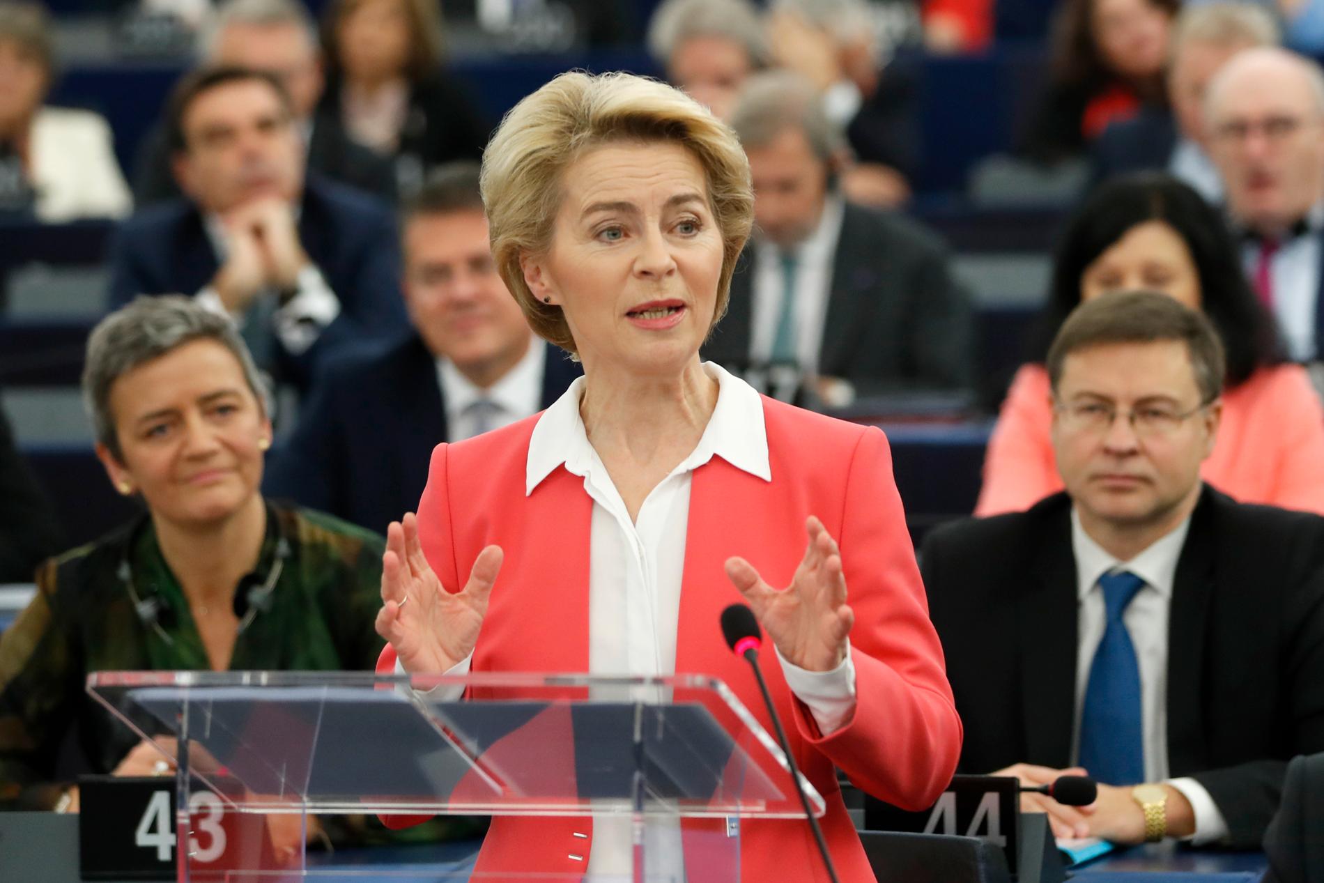EU:s tillträdande kommissionsordförande Ursula von der Leyen talar i EU-parlamentet. Bakom henne syns den exekutiva viceordföranden Margrethe Vestager (till vänster) och Valdis Dombrovskis (till höger).
