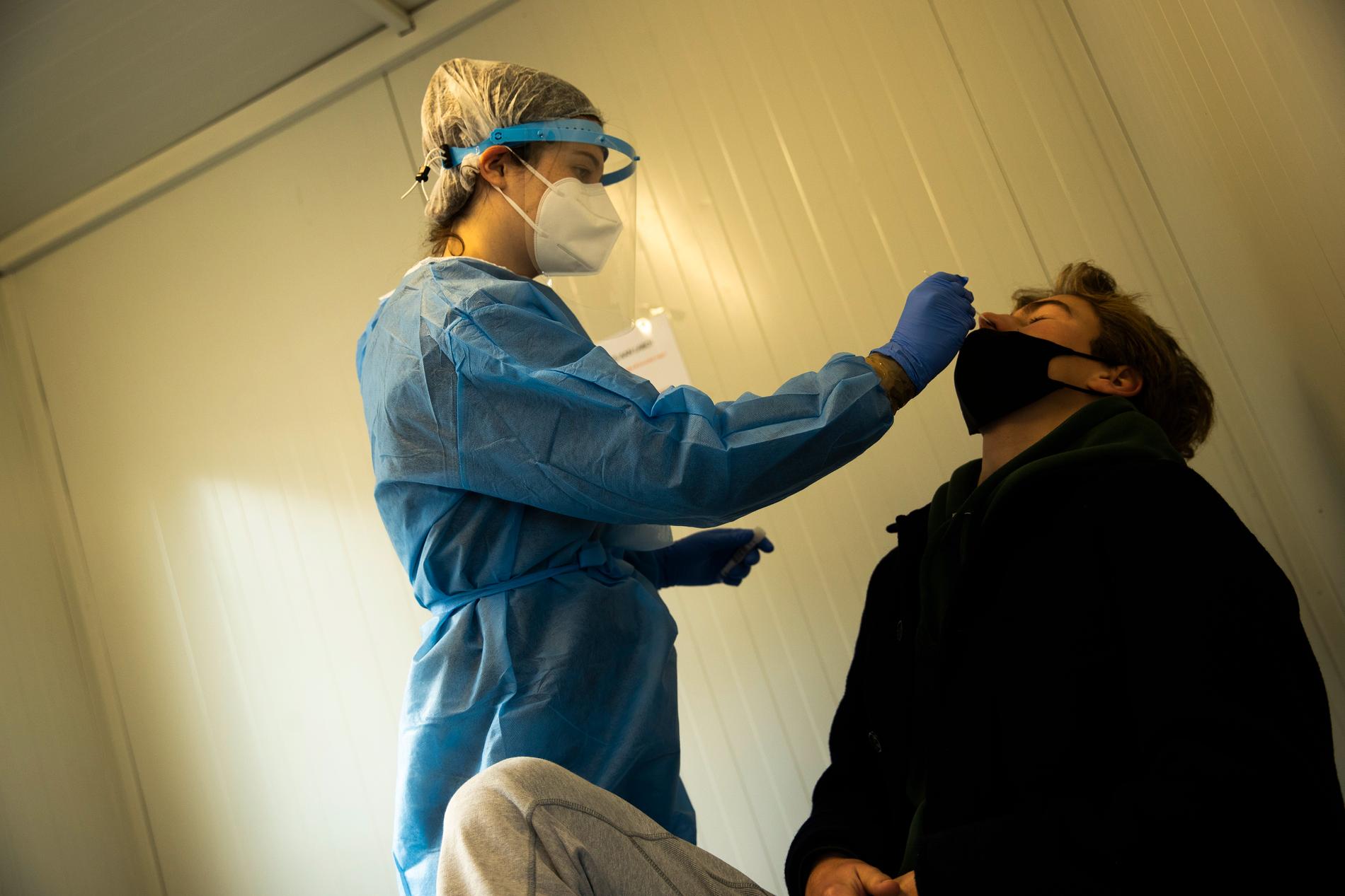 En sjukskötare coronatestar en resenär på Brysselflygplatsen Zaventem i Belgien.