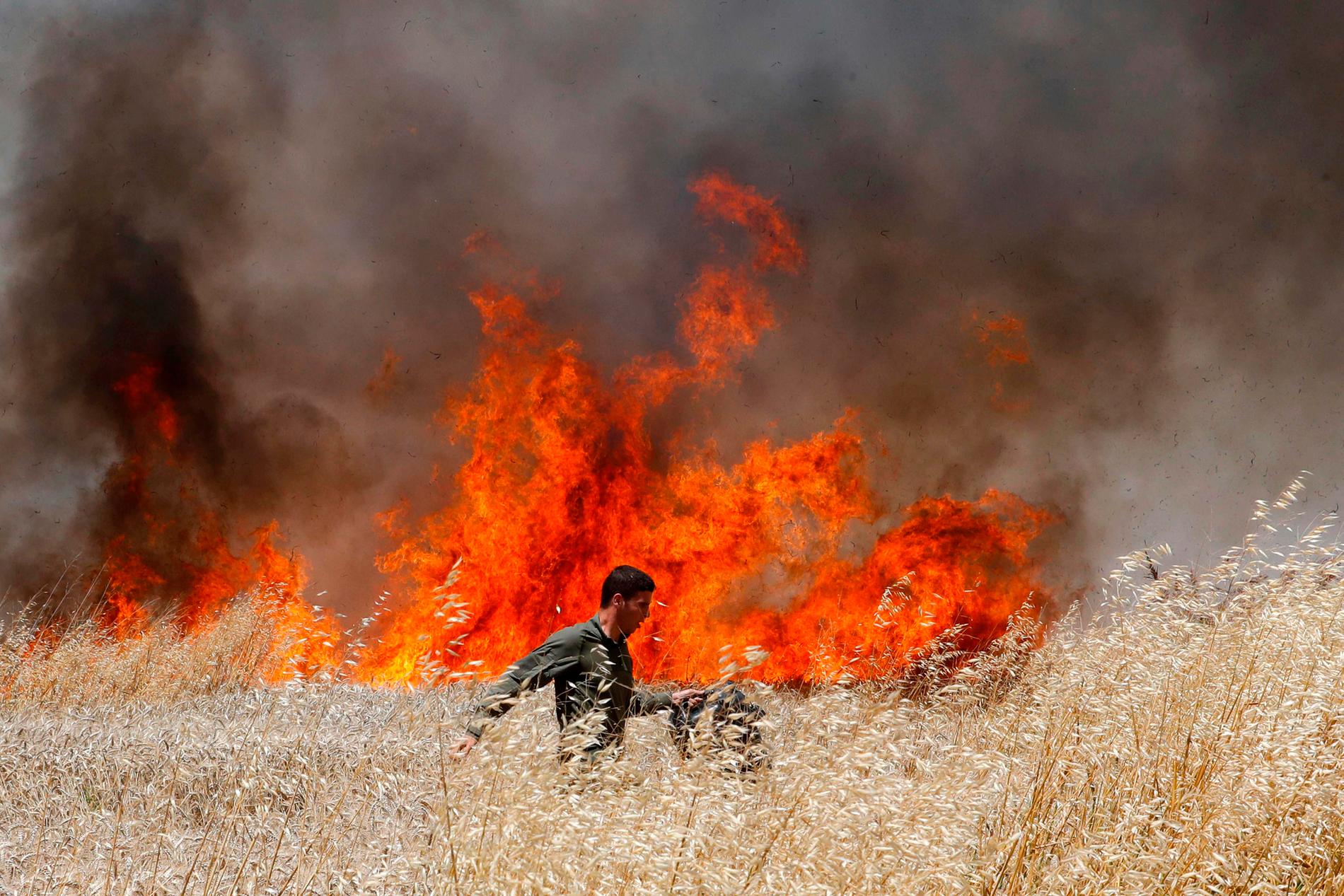 En israelisk soldat försöker släcka en eld på ett fält i närheten av gränsen mot Gazaremsan. 