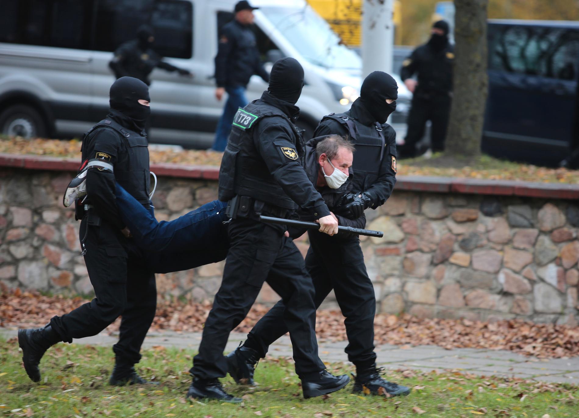 En man bärs iväg i armar och ben vid en demonstration i Minsk, den 1 november i fjol. Arkivbild.
