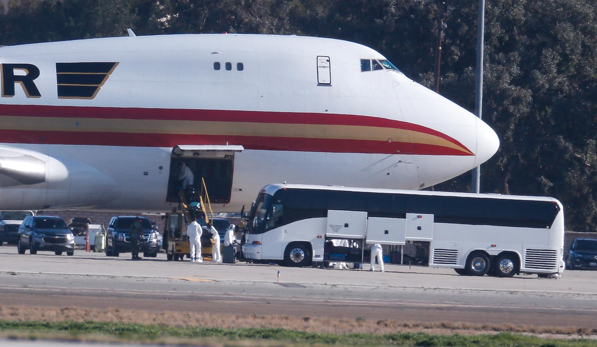 Personal i skyddskläder tar emot personer som evakuerats från Wuhan, Kina, i Kalifornien. 