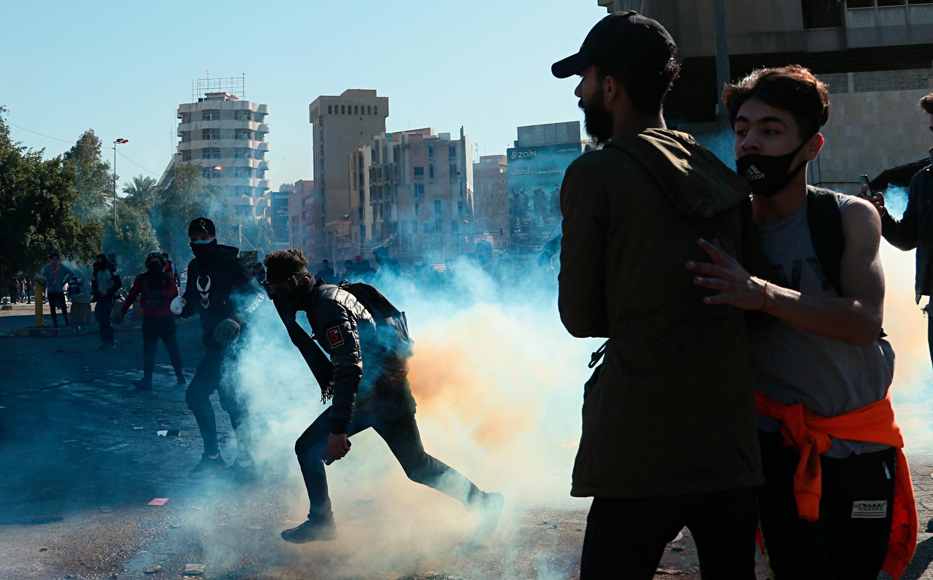 Regeringskritiska demonstranter flyr undan säkerhetsstyrkornas tårgas vid protester i Bagdad på söndagen.