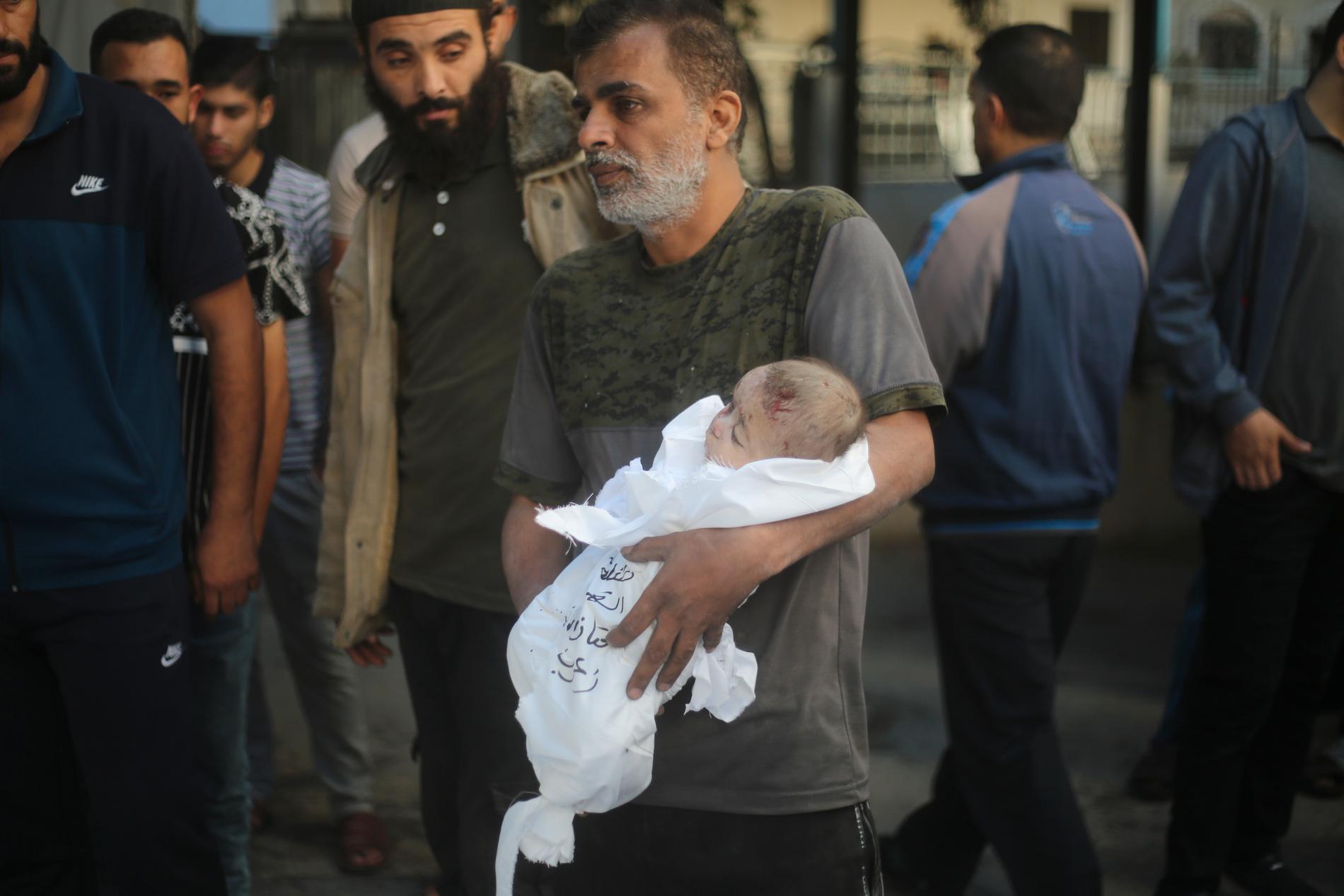 En man bär på ett dött barn i Gaza.