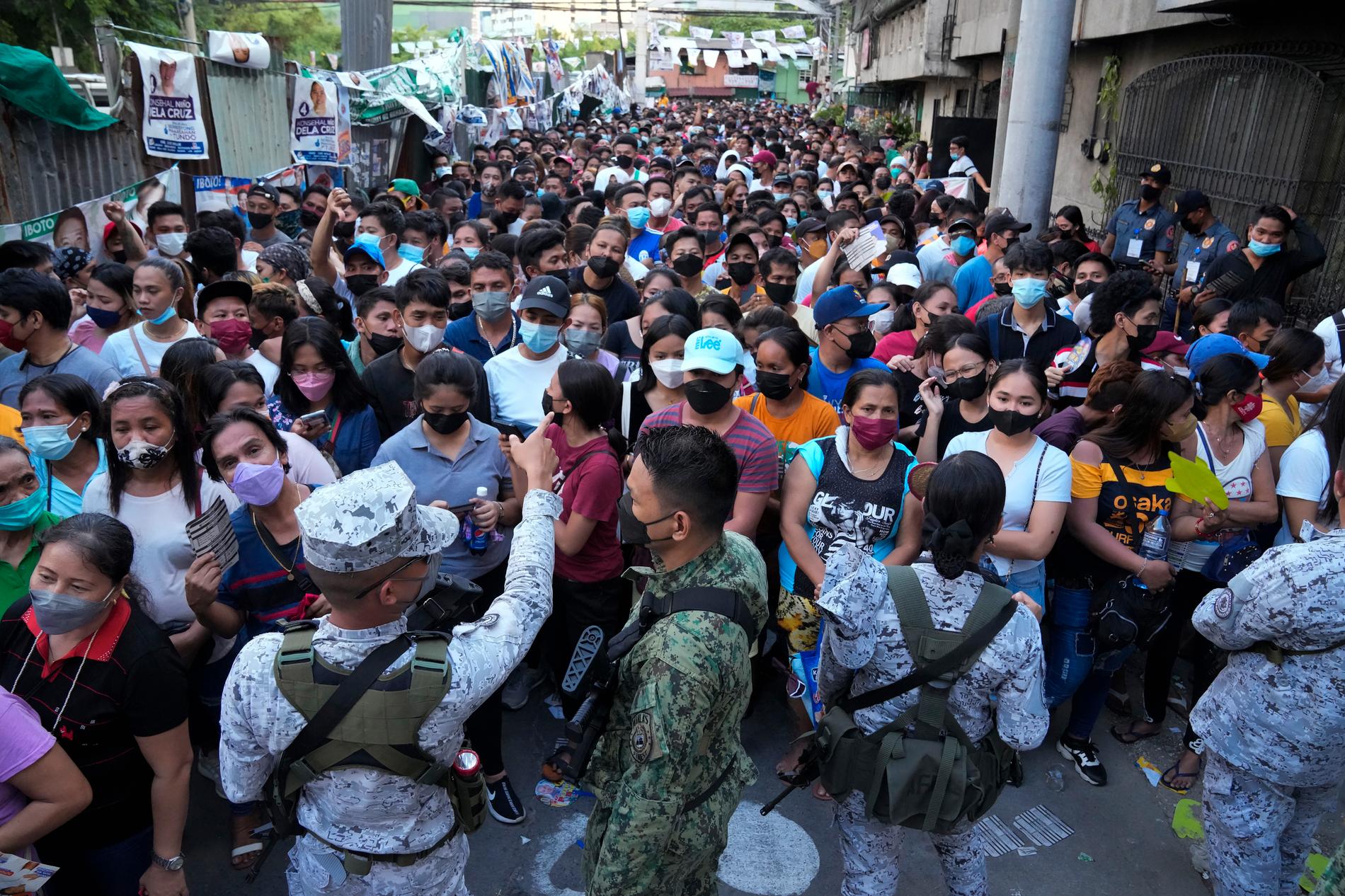 Polis och filippinska marinsoldater försöker kontrollera en folkmassa som väntar på att få rösta i huvudstaden Manila.