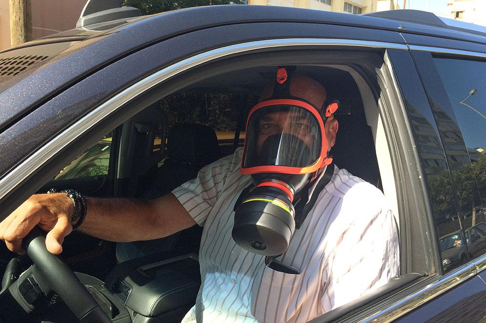 En libanesisk doktor bär en gasmask som skydd mot lukten när han kör genom Beirut.