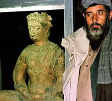 En oidentifierad talibansk ämbetsman vid sidan av en Buddha-staty på Nationalmuseum i Kabul. Statyn anses strida mot islam och ska därför slås sonder.