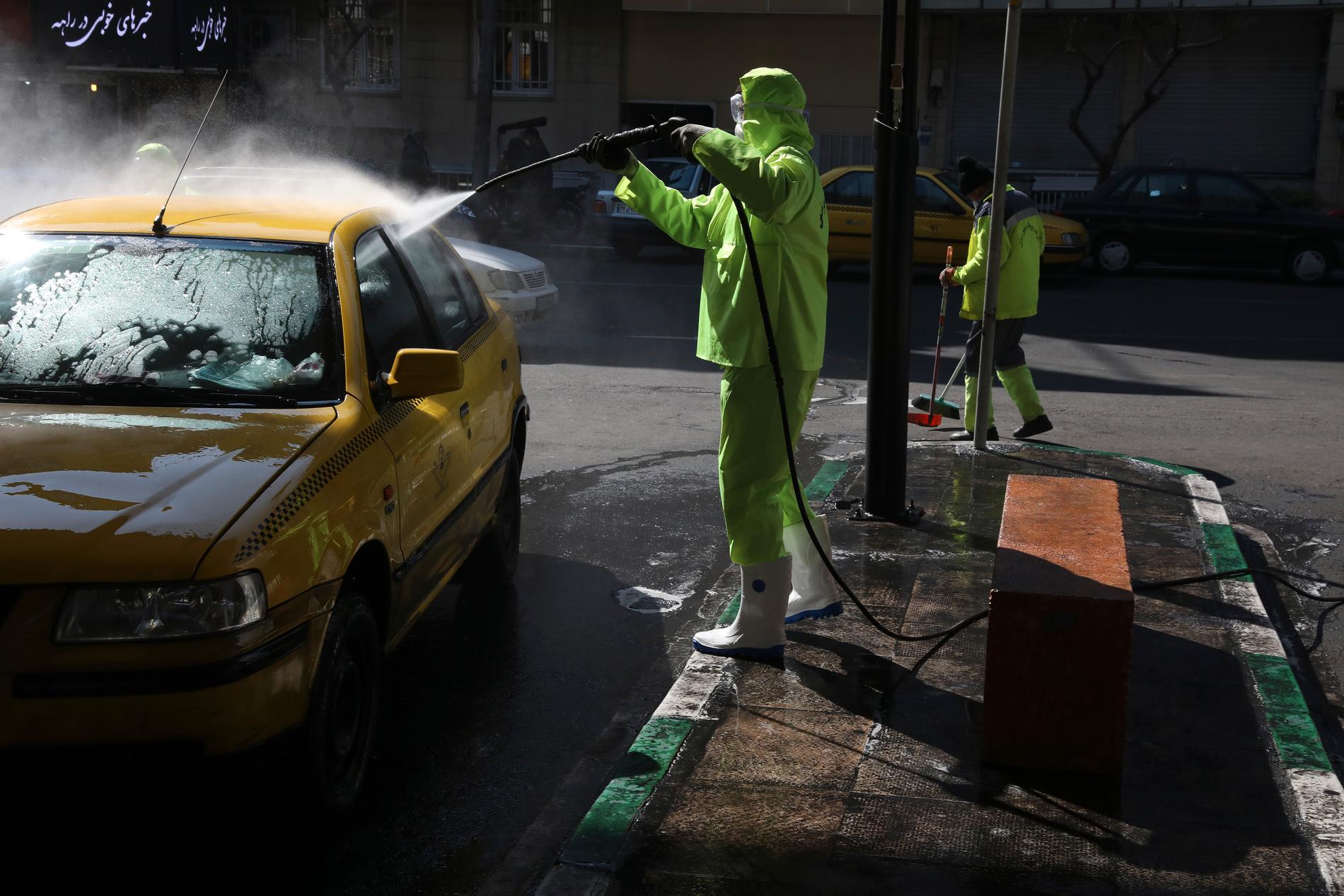 En renhållningsarbetare sprutar desinficeringsmedel på en taxi i Teheran i måndags.