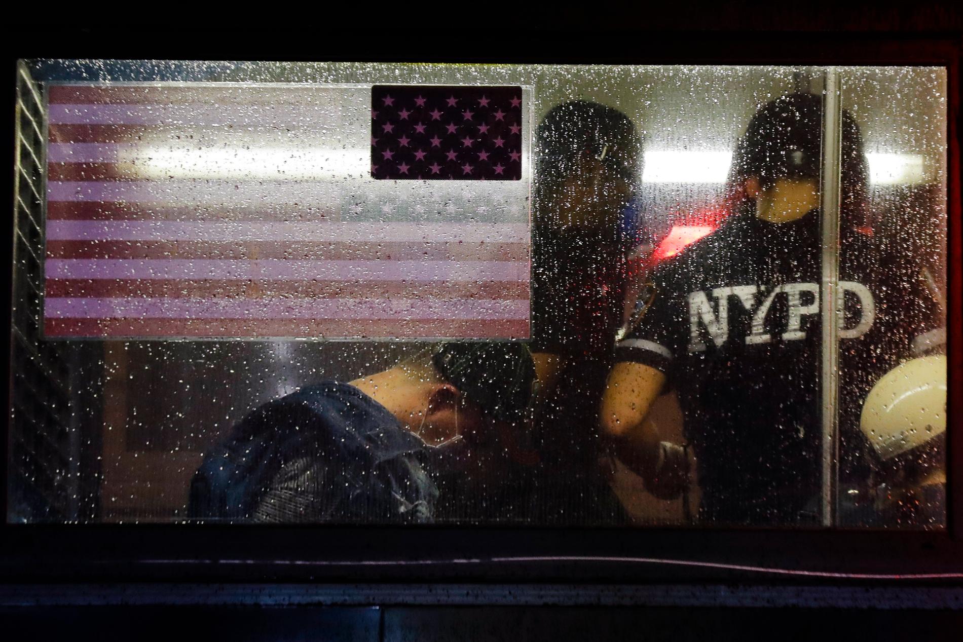 En polis talar med en gripen person i en buss under protesterna i New York. Arkivbild.