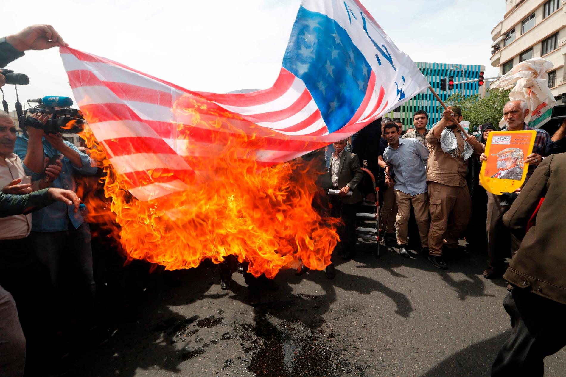 Demonstranter tänder eld på en amerikansk flagga i Irans huvudstad Teheran under fredagen. 
