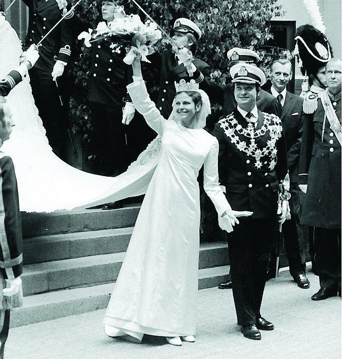 Drottning Silvia bar en benvit klänning från modehuset Dior, prinsessan Sibyllas kamédiadem och en brudbukett av vita orkidéer när hon stod brud i Storkyrkan 1976.